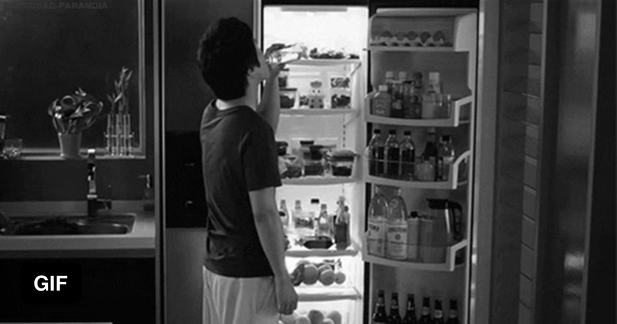 Пирсингованная неформалка с дредами стоит возле холодильника без трусов и лифчика