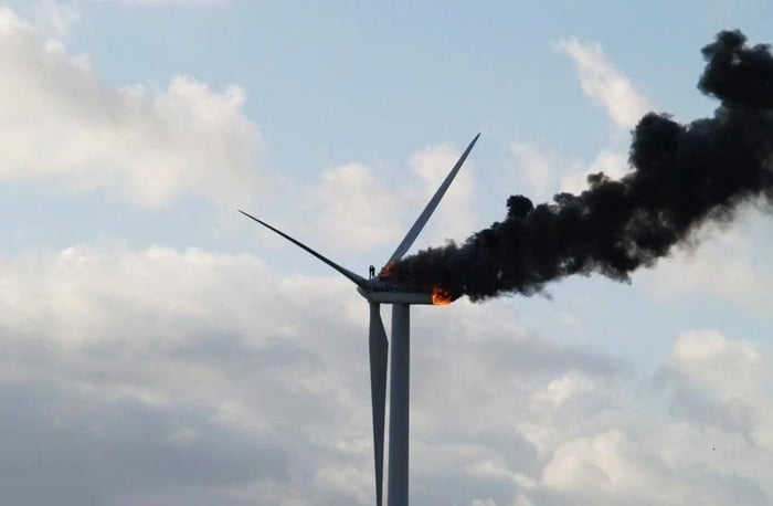 Two Engineers Sharing A Hug Atop A Burning Wind Turbine During Their 