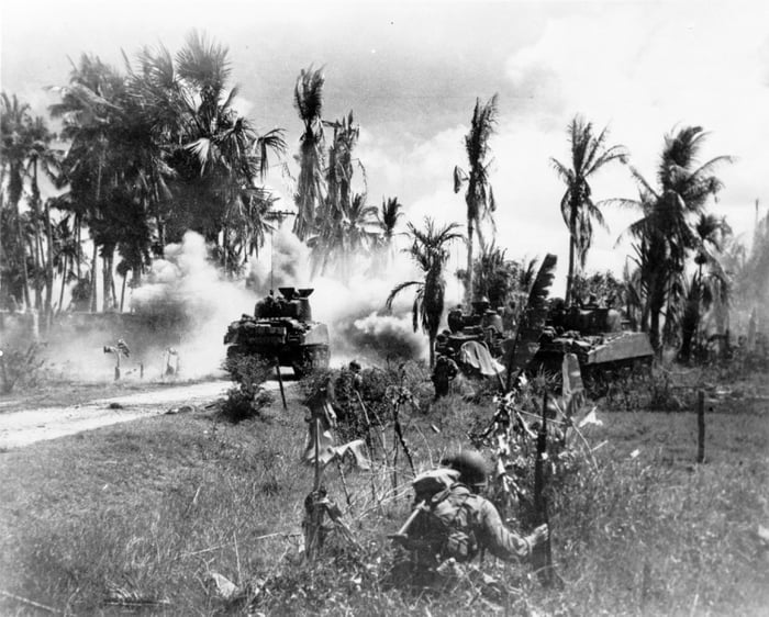 Troops of the 185th Inf., 40th Div., take cover behind advancing M4 ...