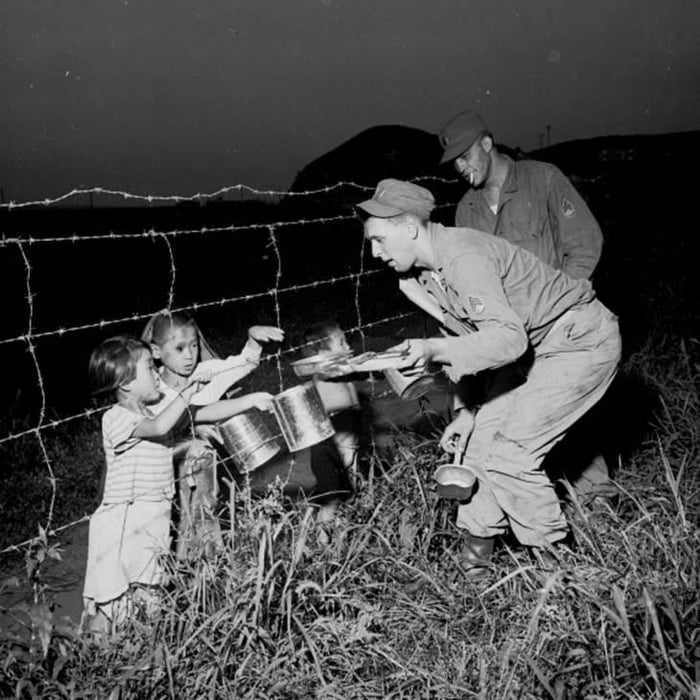 two-u-s-army-staff-sergeants-passing-food-through-a-barbed-wire-fence