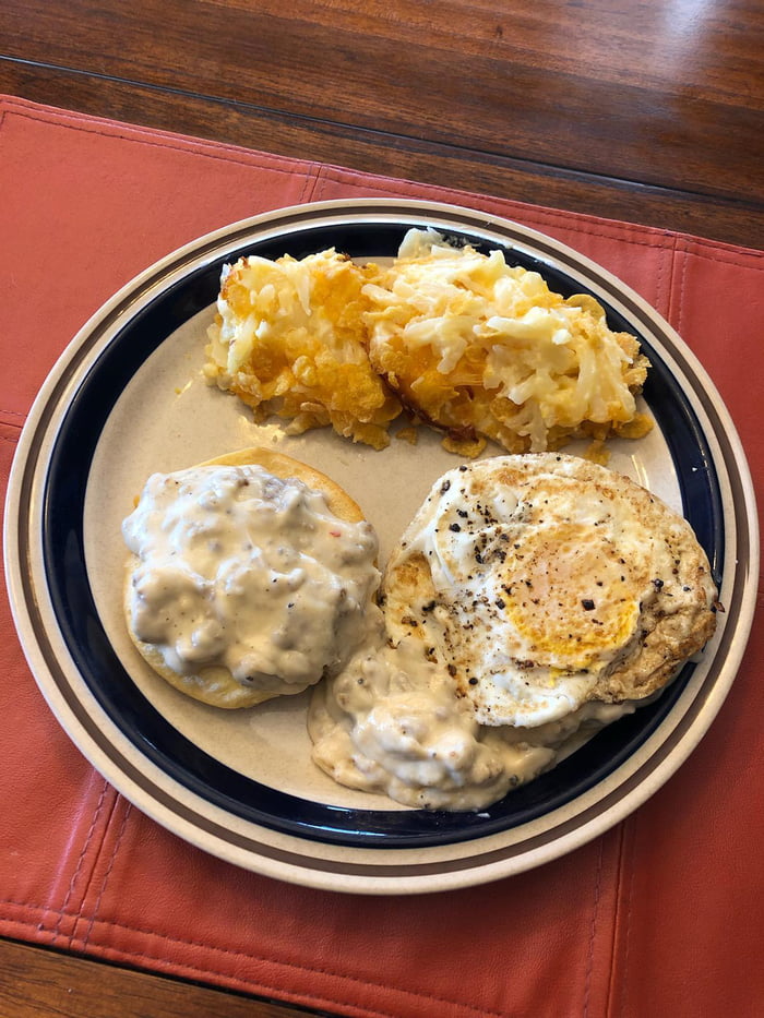 Biscuits and gravy topped with an egg with a side of cornflake potatoes ...