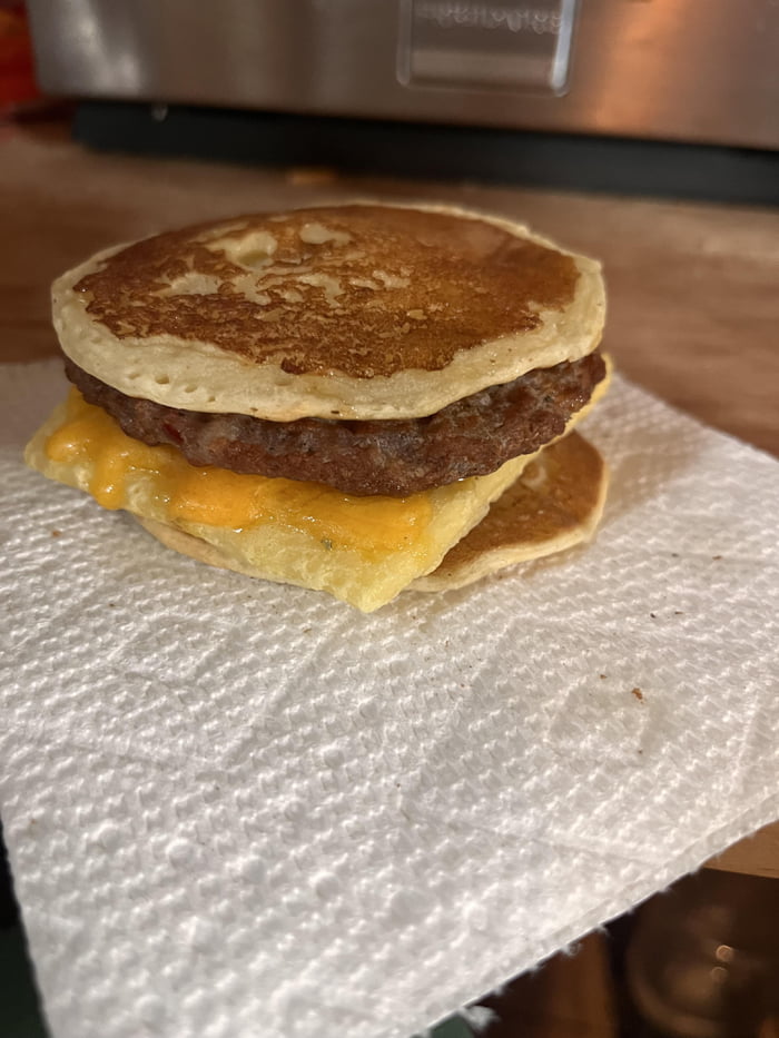 GF pancake sandwich with Just Egg patty product, shredded cheddar, sausage patty, and real maple