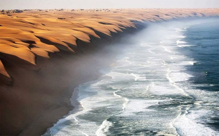 The high sand dunes of Namib desert meeting the sea. The coastal desert ...