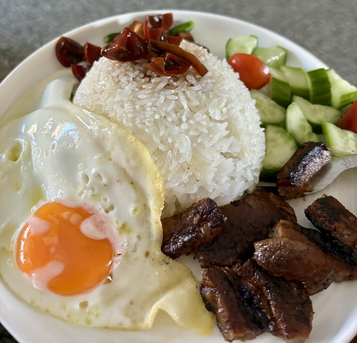 Filipino Breakfast of grilled meat, egg, rice, cucumber salad, and a ...