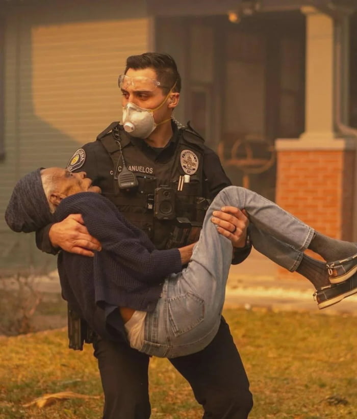 A white male police officer saving a man from a burning building. This ...