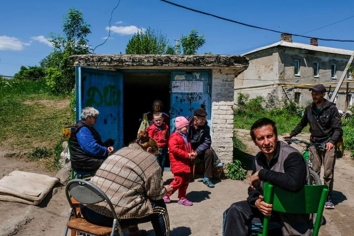 People sit in front of a bunker where they live in the outskirts of the ...